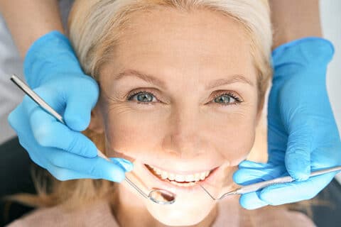 Kvinde til tandeftersyn hos tandlæge med blå handsker – eksempel på forebyggende tandpleje i København.