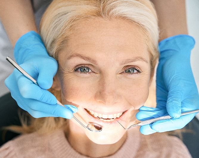 Kvinde til tandeftersyn hos tandlæge med blå handsker – eksempel på forebyggende tandpleje i København.