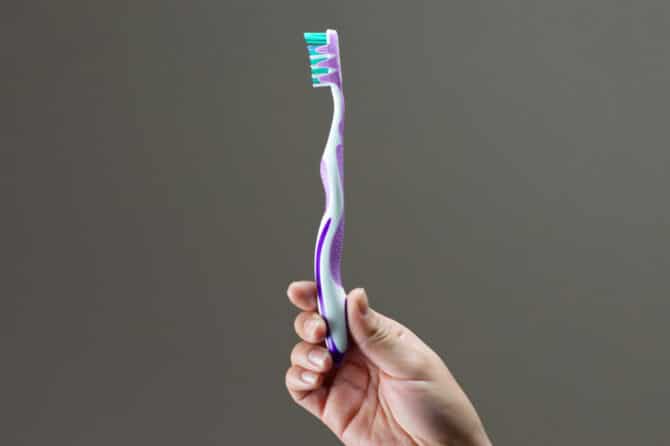 En person holder en tandbørster i forbindelse med daglig tandpleje.