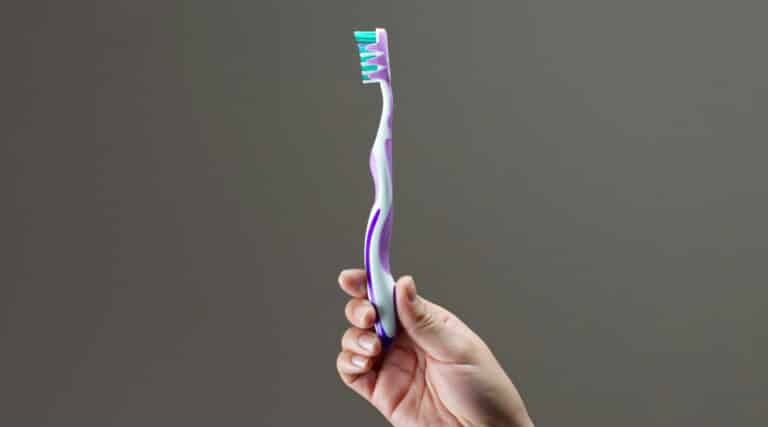 En person holder en tandbørster i forbindelse med daglig tandpleje.